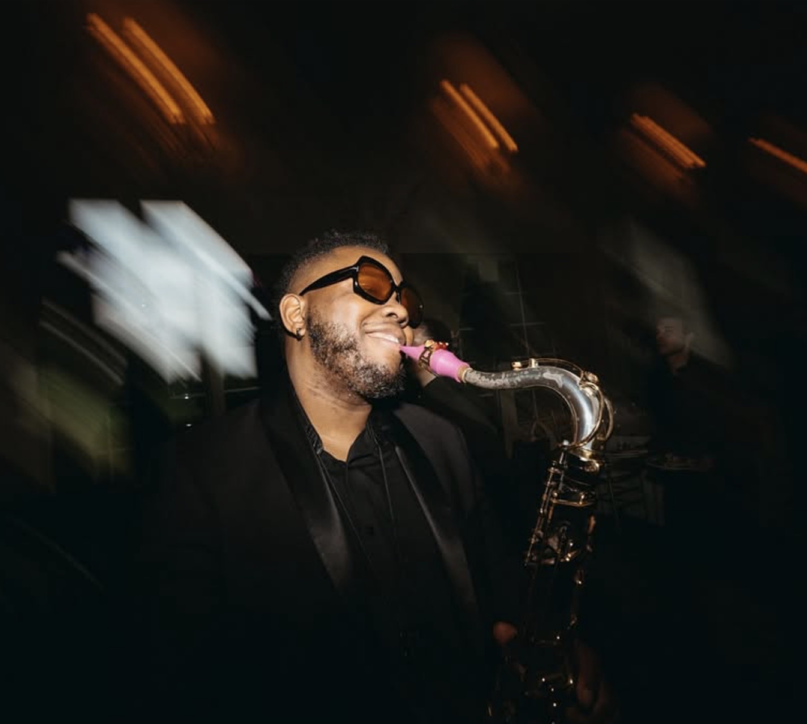 A saxophonist performing live at an event under warm lighting
